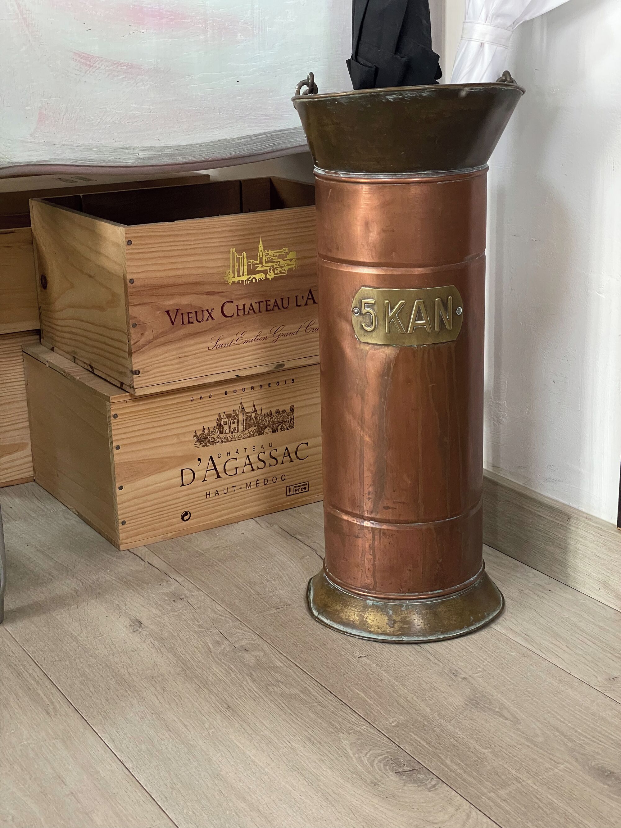 A wooden crate with a label reading "Vieux Chateau L'A" and a copper container with a label "5KAN".