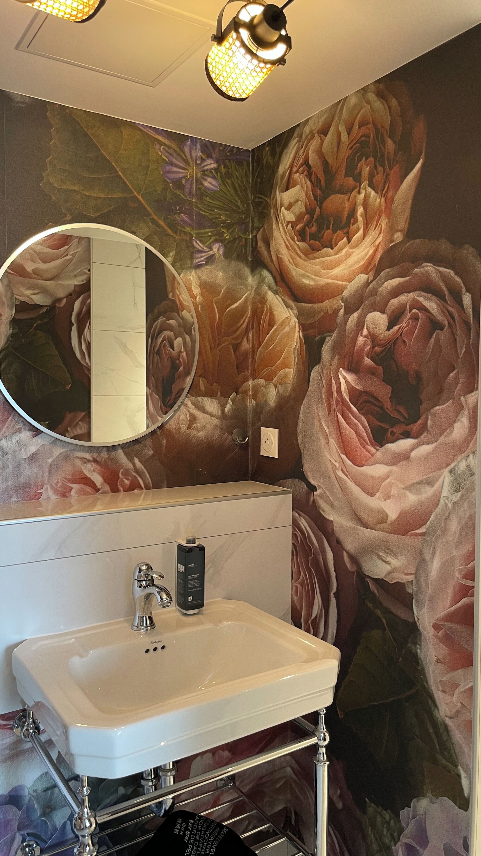 A bathroom with a white sink, a mirror, and a floral mural on the wall.