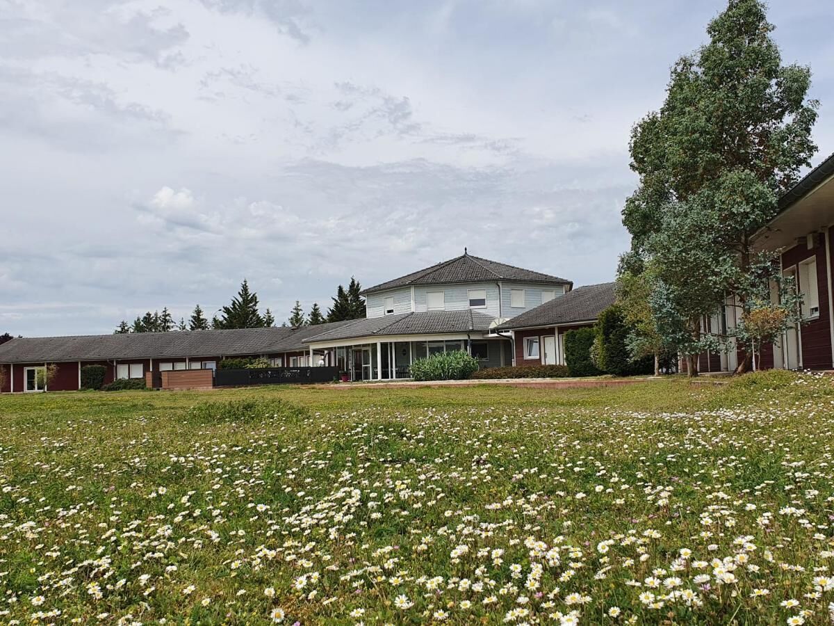 Zona residencial amb un gran jardí i una casa amb teulada inclinada.