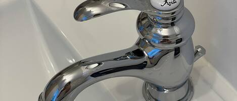 A chrome faucet with a lever handle and a control knob labeled "Foil" on a white sink.