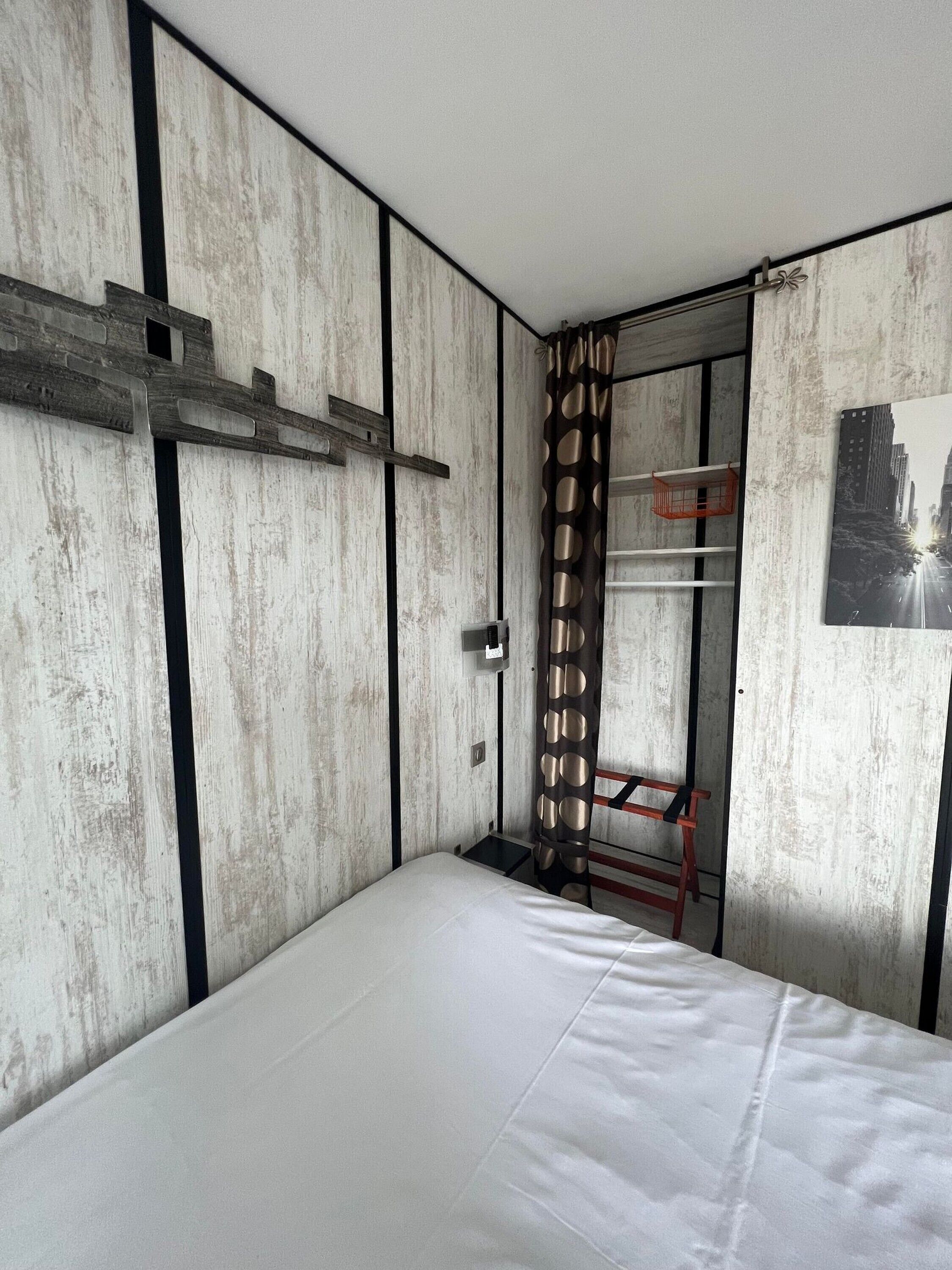 A bedroom with a bed, a wardrobe, and a door leading to another room.
