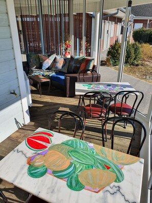 An outdoor seating area with a table and chairs, a sofa with colorful cushions, and a decorative vase with flowers. - Eqynox Hôtel (Marolles)