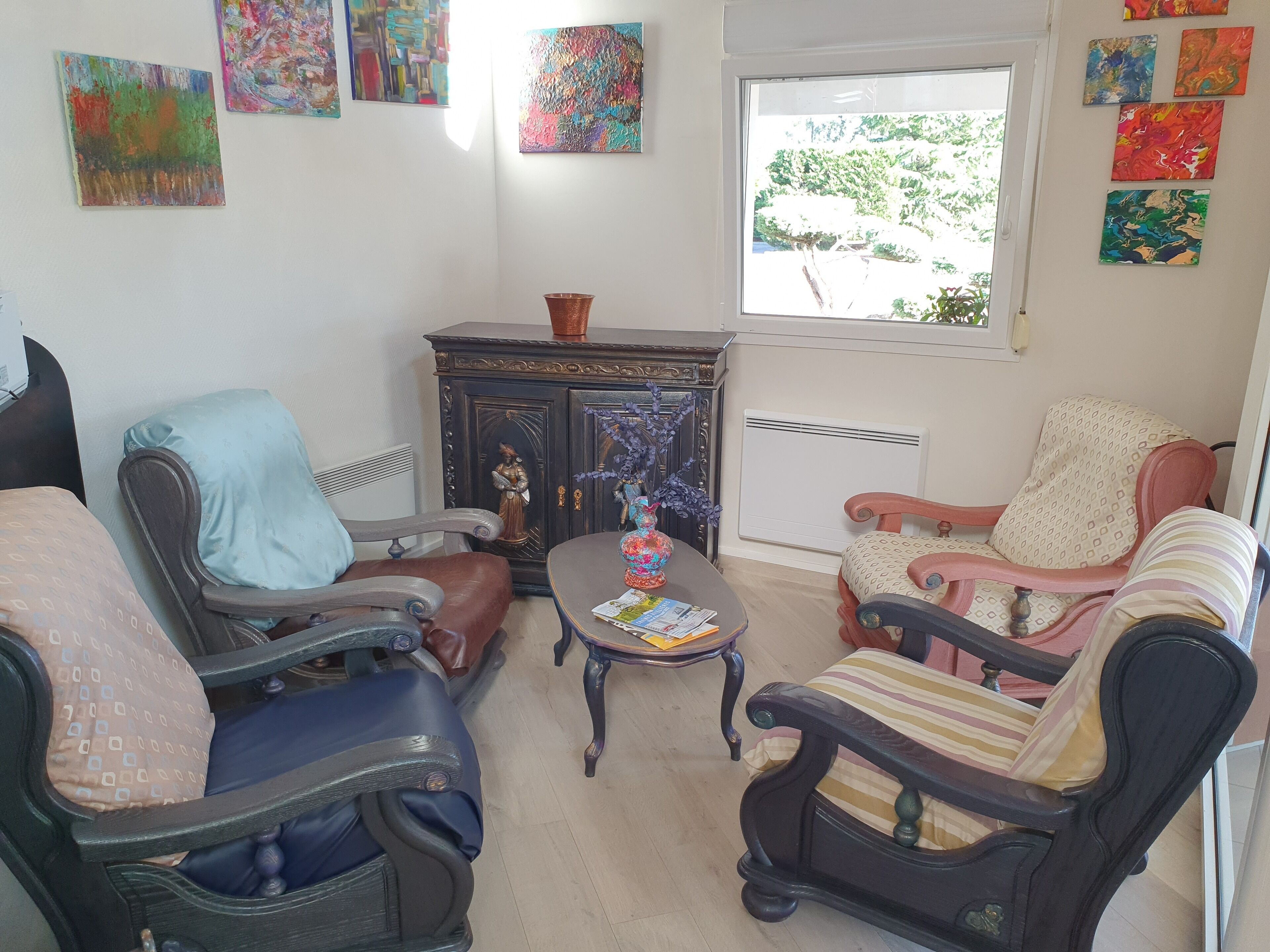 A living room with two armchairs, a small table, and a cabinet with decorative items.