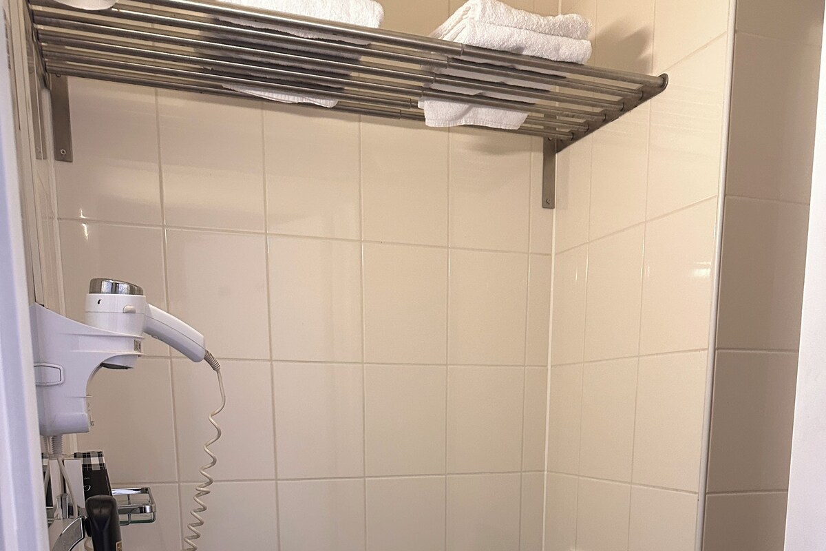 Ein kleines Badezimmer mit Toilette, Waschbecken, Fön und Handtuchhalter.