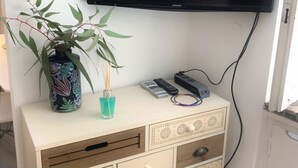 A TV mounted on a wall above a cabinet with drawers and a vase with a plant.