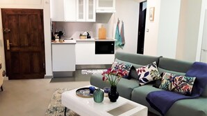 A living room with a sofa, a coffee table, and a kitchen area in the background.