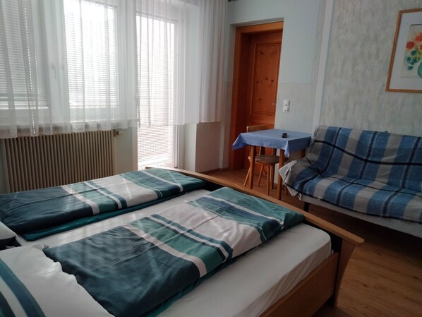 Una habitación con dos camas, un sofá, una mesa y una puerta.