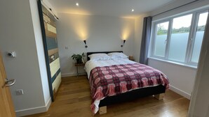 Ein Schlafzimmer mit Bett, Nachttisch, Blumentopf und Fenster mit Blick.