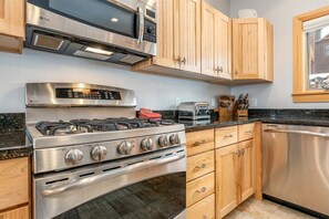 A kitchen with stainless steel appliances, wooden cabinets, a toaster, and a dishwasher.