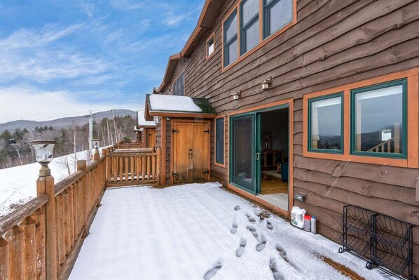 A wooden cabin with a deck, a sliding glass door, and a snow-covered ground. - Tempest Ridge Townhouse 18 (Newry)