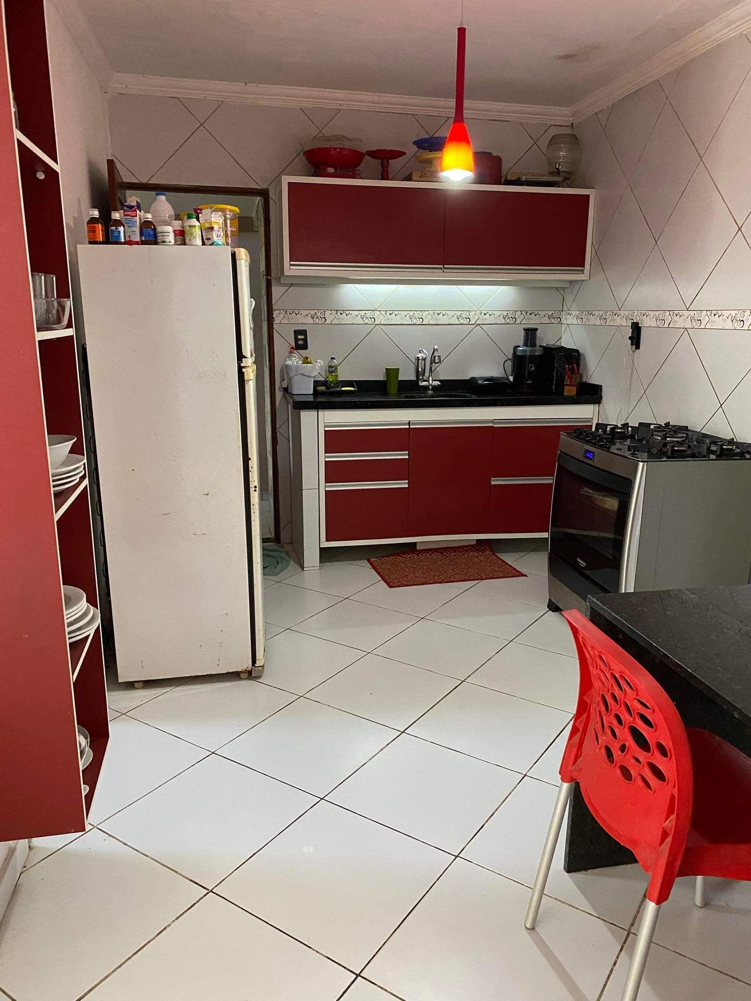 Une petite cuisine équipée d’un réfrigérateur, d’une cuisinière et d’une chaise rouge.