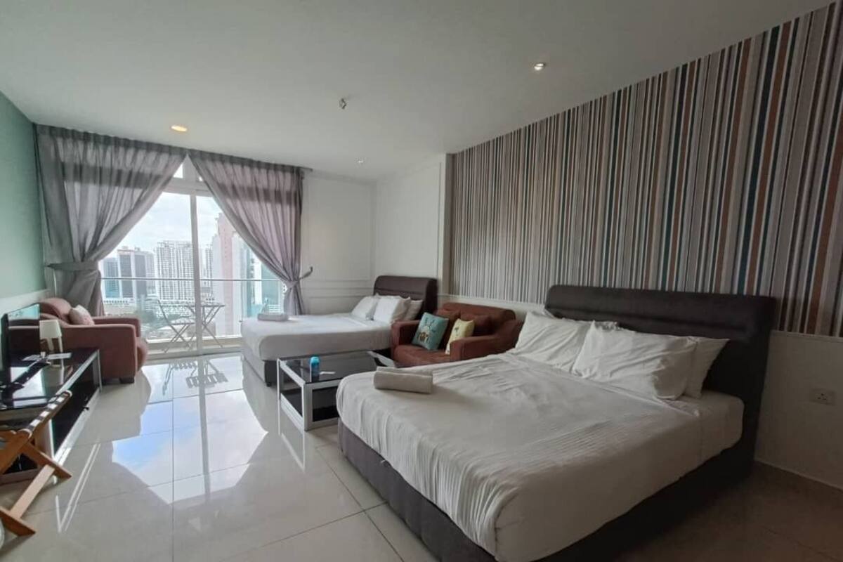 A modern hotel room with a large bed, a sofa, a desk, and a view of the city.