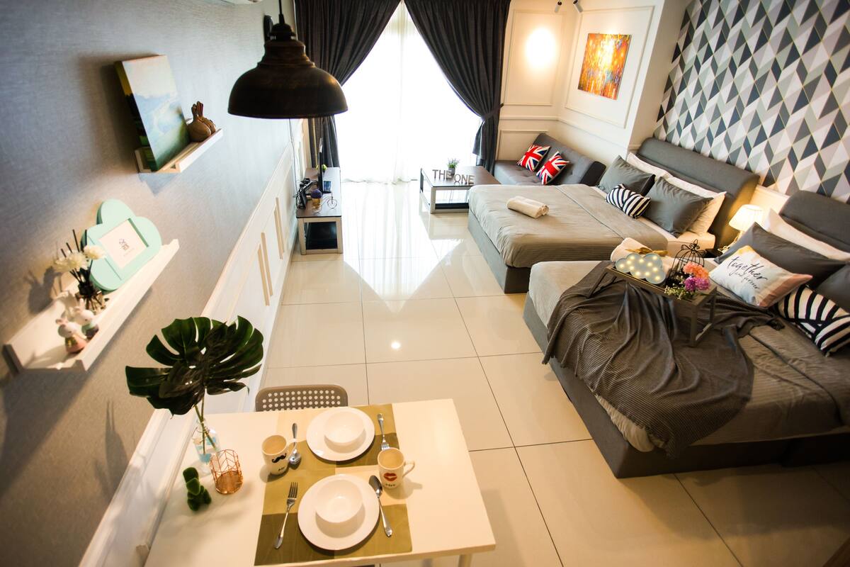 A modern hotel room with a dining area, a sofa bed, and a large window with curtains.
