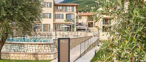 A hotel with a pool, outdoor seating, and a mountainous backdrop.