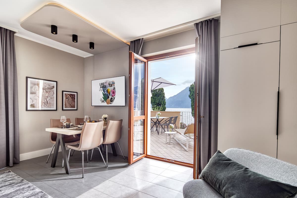 Ein modernes Wohnzimmer mit einer Couch, einem Essbereich mit Stühlen und einem Tisch sowie ein Balkon mit Sitzgelegenheit.