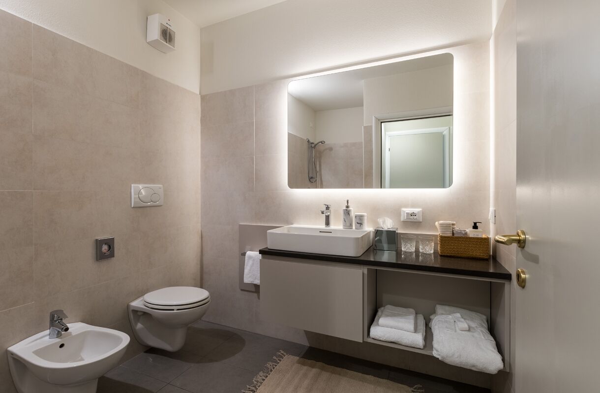 Et moderne badeværelse med toilet, bidet, vask og underskab.