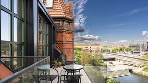 A balcony with a glass railing overlooking a river and buildings. - RentPlanet - Bulwar Staromiejski (Wroclaw)