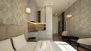 A modern hotel room with a large bed, a small kitchen area, a seating area, and a bathroom. - RentPlanet - Bulwar Staromiejski (Wroclaw)