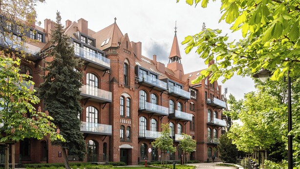 A large brick building with multiple balconies and a tower. - RentPlanet - Bulwar Staromiejski (Wroclaw)