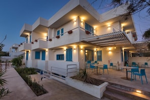 A modern building with multiple balconies, outdoor seating, and a covered patio area.