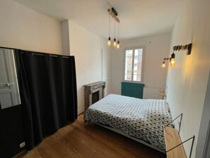 A small, compact bedroom with a bed, a window, and a fireplace.