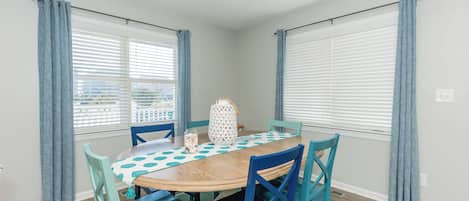 A dining area with a round table, blue chairs, and a white patterned table runner.