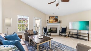 A living room with a sofa, chairs, a coffee table, a fireplace, and a TV.
