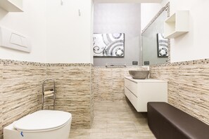 A bathroom with a toilet, sink, and bench.