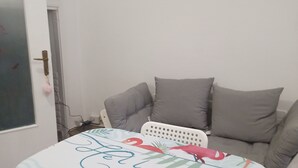 Et værelse med en seng, en sofa og en stol. Der er en dør med håndtag og en nøglering.