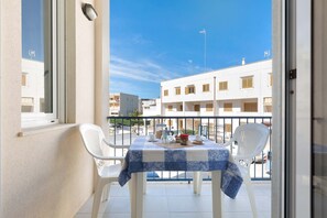 Enjoy a romantic meal for two on this balcony with a table set amidst a picturesque cityscape.