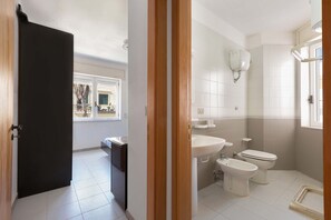 Een badkamer met toilet, hygiëneschuimer en wastafel.