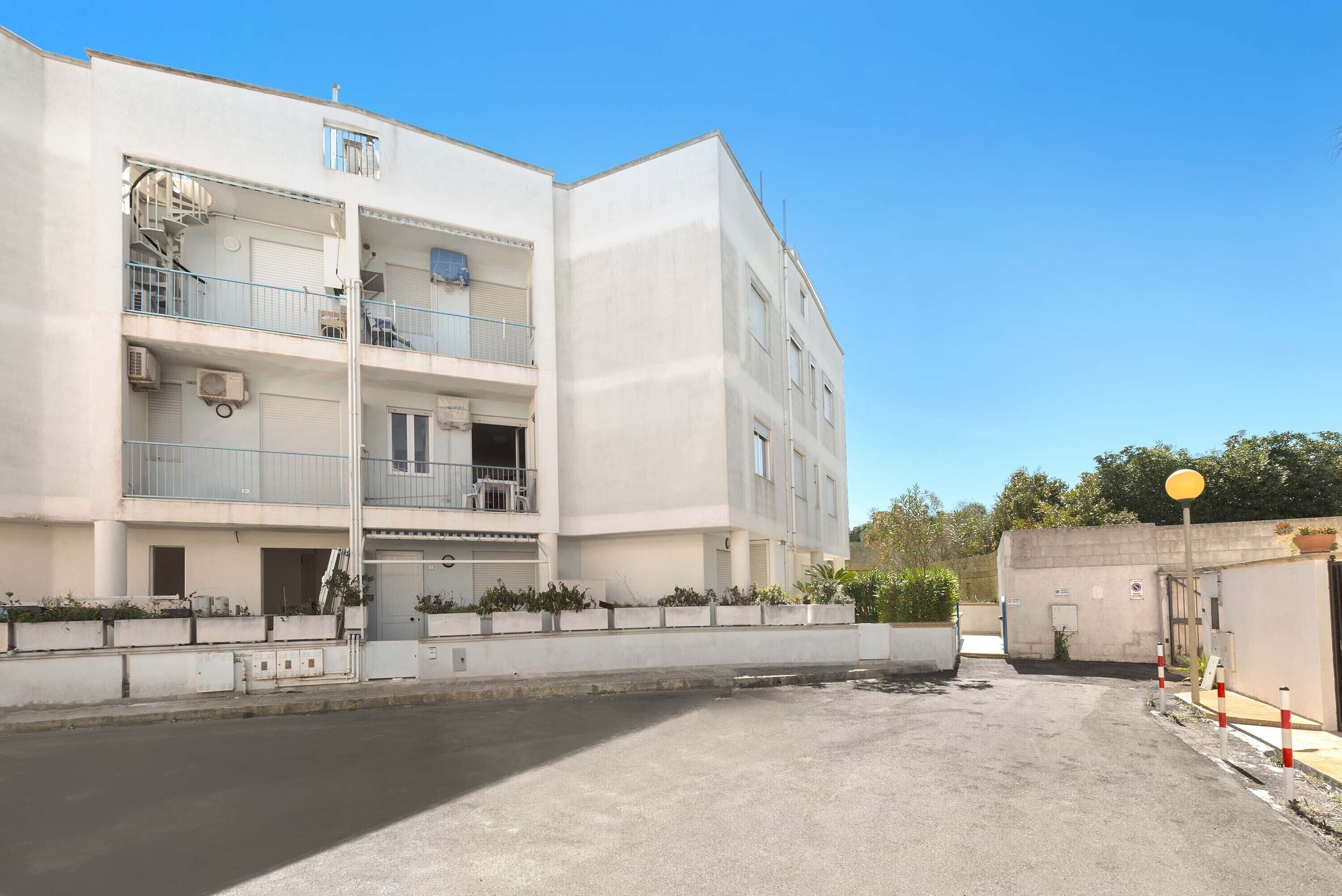 A multi-story building with balconies, air conditioning units, and a gated entrance.