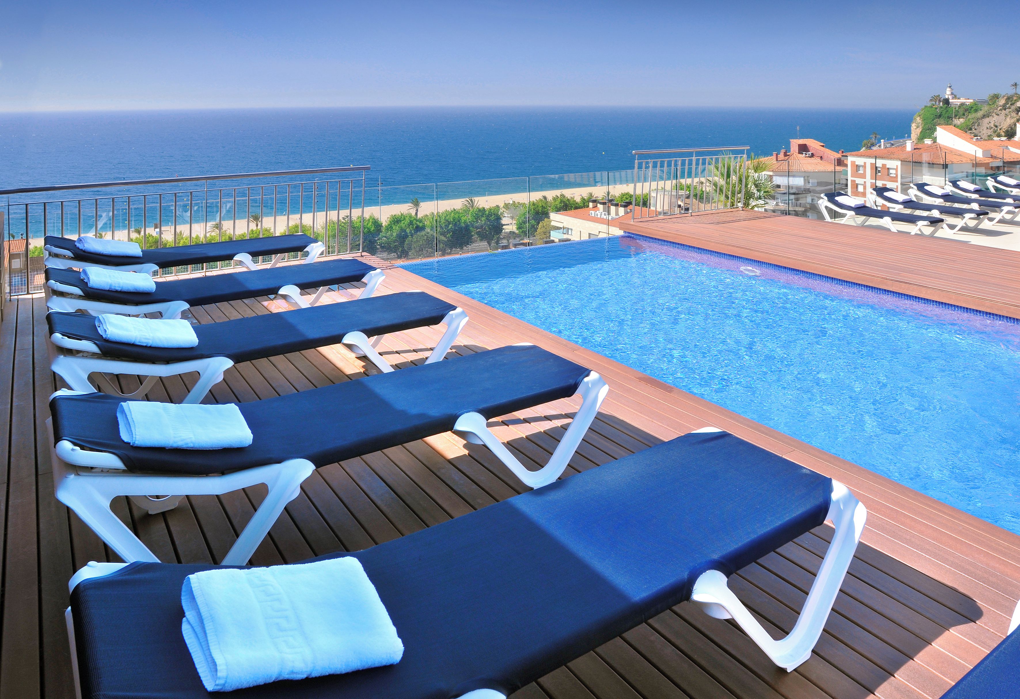Ein Poolbereich mit Liegestühlen und Blick auf den Ozean.