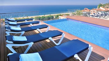 Ein Poolbereich mit Liegestühlen und Blick auf den Ozean.