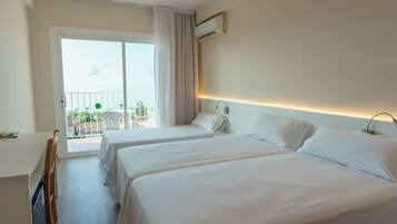 Una habitación de hotel con dos camas, un balcón con una silla y vistas al mar.