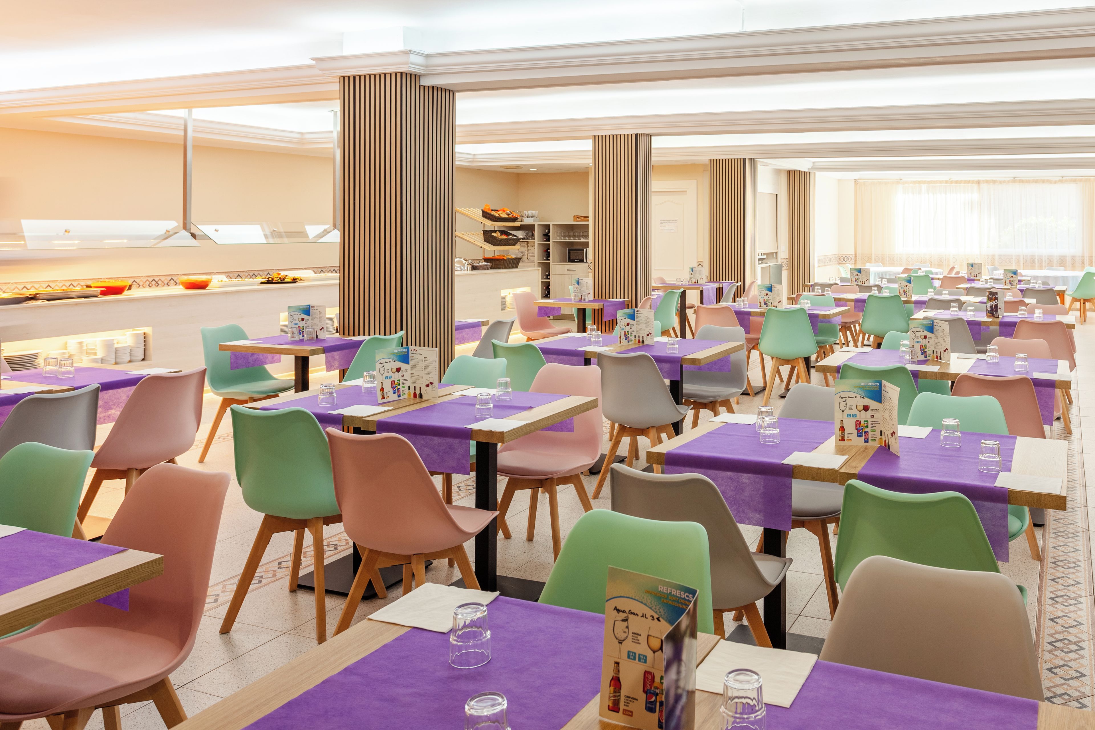 Un comedor amplio con múltiples mesas y sillas, una barra de buffet y un diseño interior moderno.