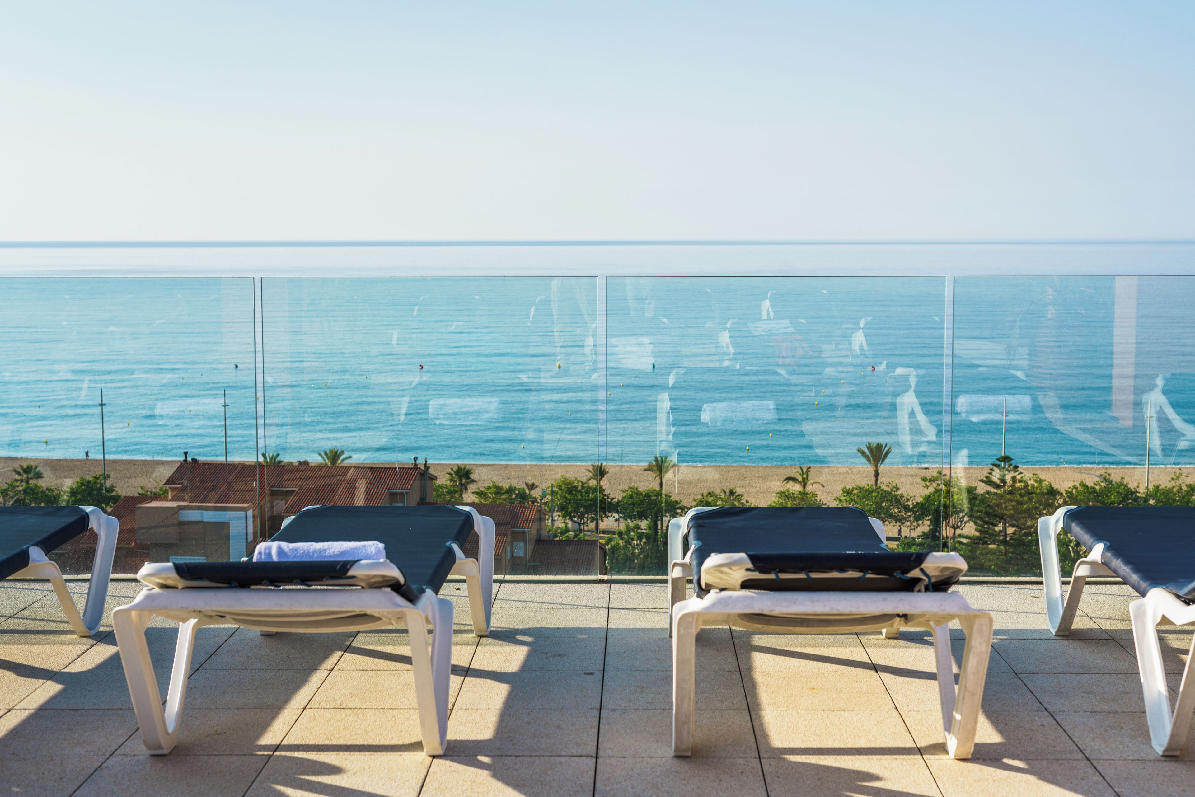 Una terraza con sillones de descanso frente a una playa y el mar.