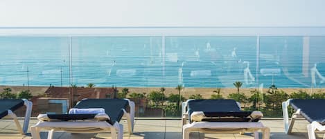 Una terraza con sillones de descanso frente a una playa y el mar.