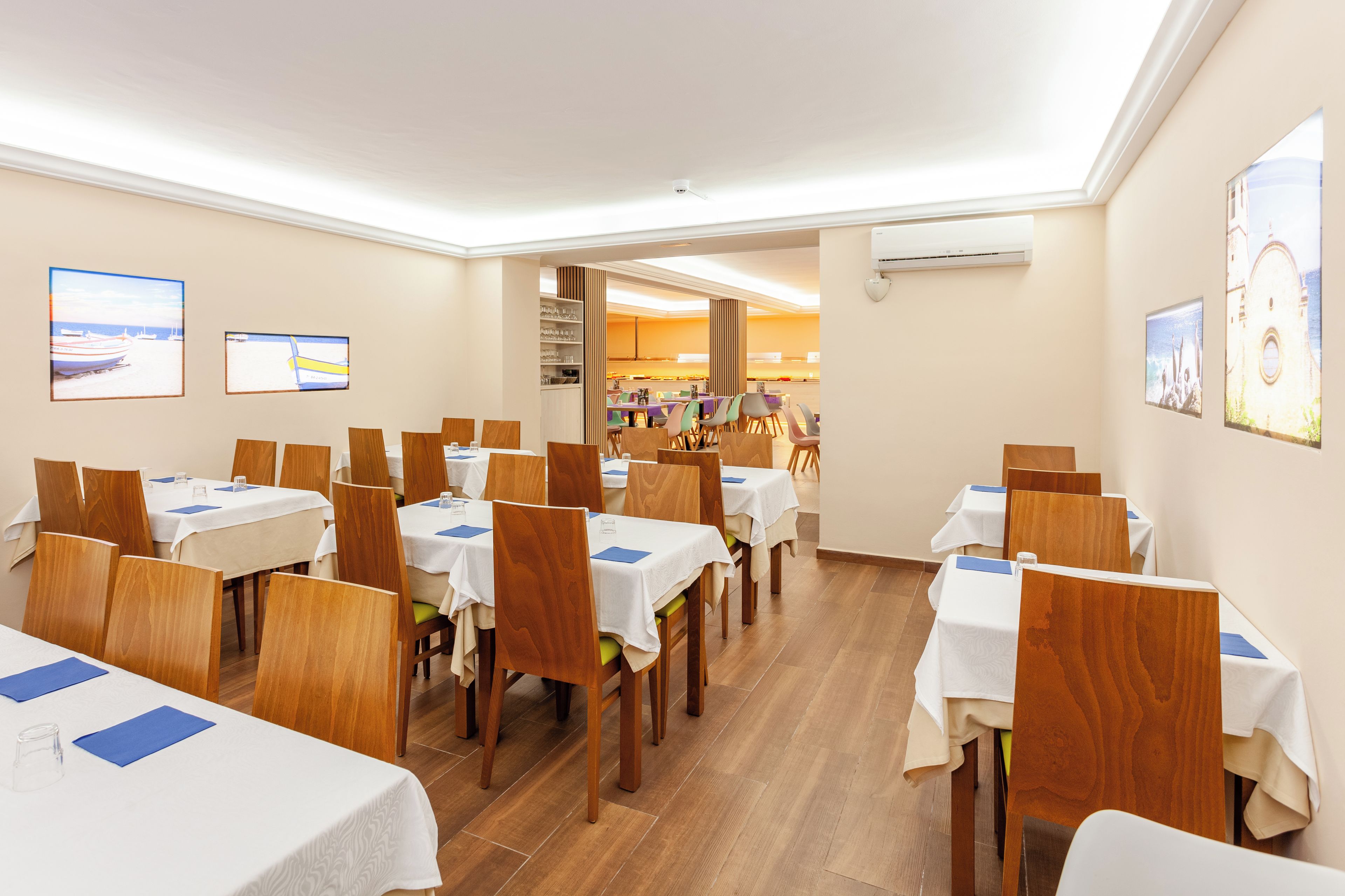Un comedor con varias mesas y sillas, dispuestas en filas.