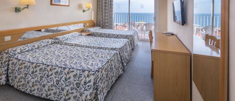 Ein Hotelzimmer mit Balkon, zwei Betten mit Blumenmuster sowie Schreibtisch und Fernseher.