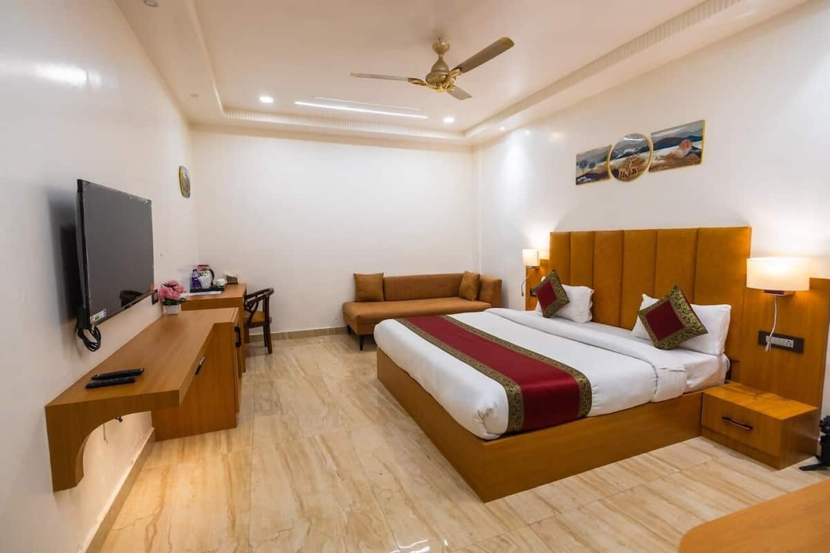 A hotel room with a bed, a desk, a television, and a sofa.