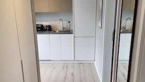 Una cocina moderna con armarios blancos, un lavamanos de acero inoxidable y piso de madera.