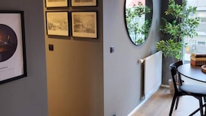 Un interior moderno con zona de comedor, obra de arte enmarcada en la pared y un espejo grande que refleja la habitación.