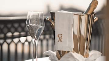Ein Tisch mit einem Glas Wasser, einer Champagnerflasche und einem Servietten auf einer runden Metalltischplatte mit einem Stuhl.