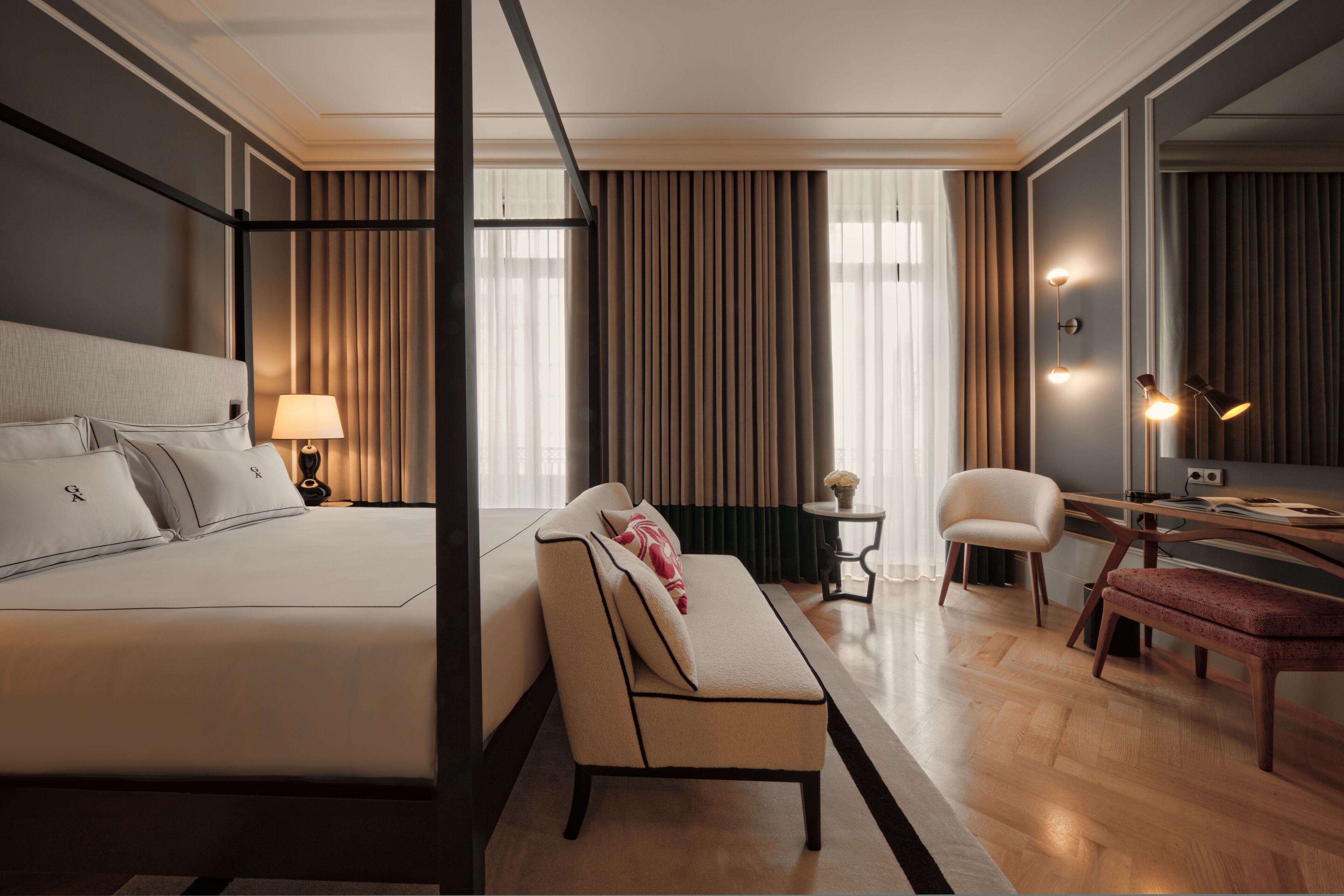 A modern hotel room with a large bed, a sofa, a desk, and a chair.