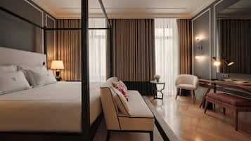 A modern hotel room with a large bed, a sofa, a desk, and a chair.