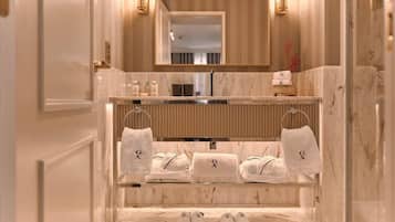 A modern bathroom with a marble vanity, a large mirror, and neatly arranged towels and slippers.