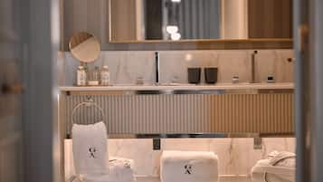 Un baño moderno con tocador de mármol, un espejo grande y dos toallas con las letras “G A”.