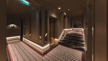 Pasillo de hotel con alfombra estampada, una escalera y una zona de recepción.