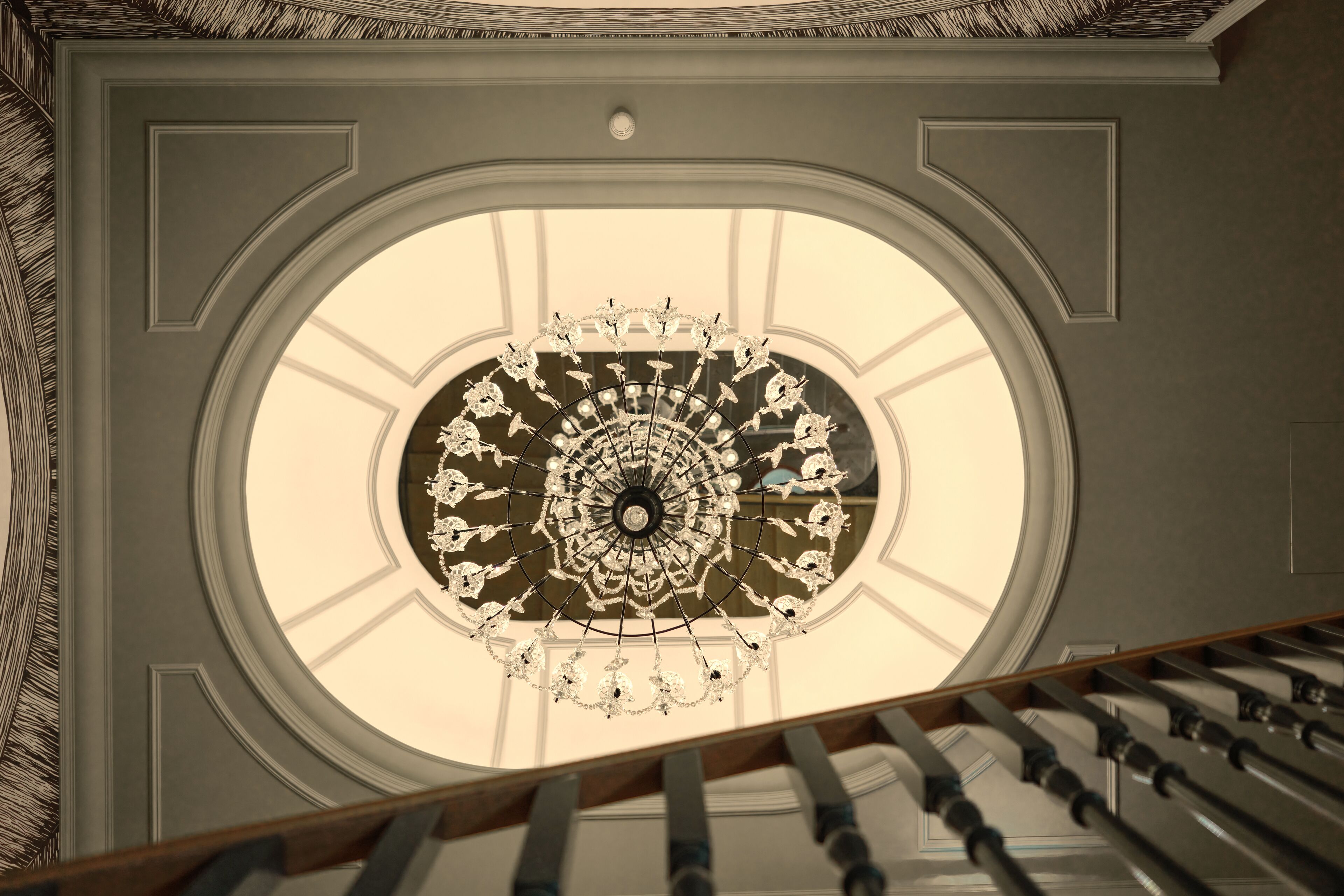 A grand, ornate ceiling with a circular skylight and a decorative chandelier.